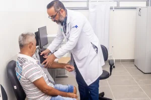Fotografia colorida mostrando médico atendendo homem em consultório-Metrópoles
